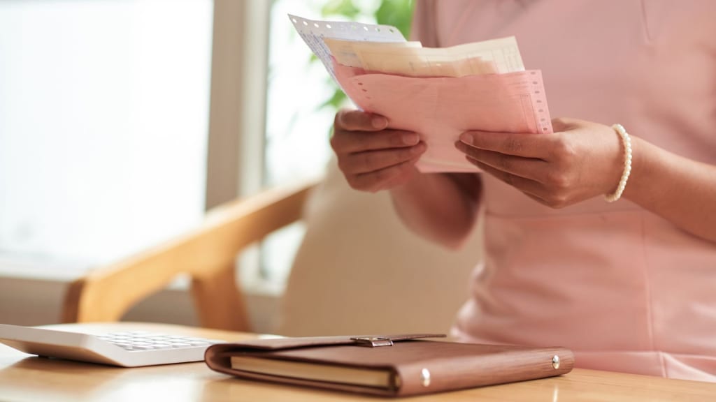 Woman organizing bills and budgeting at home, managing personal finances, highlighting issues related to financial abuse in marriage.